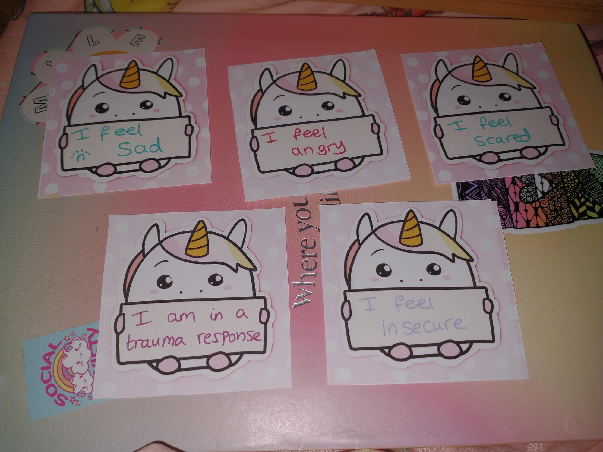 5 square communication cards with cute chubby unicorns holding blank cards. On them is handwritten; I feel sad, I feel angry, I feel scared, I am in a trauma response, I feel insecure.